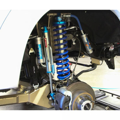 Close-up of a vehicle's suspension system with blue springs and metal components.